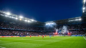 Estádio de futebol iluminado durante uma noite de Champions League com adeptos nas bancadas